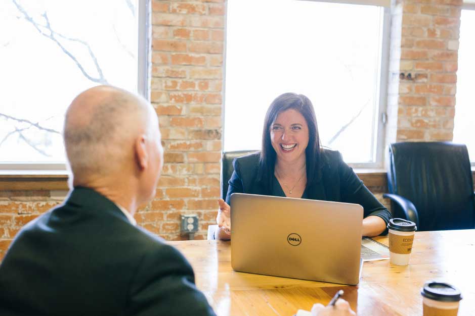Sample image of two people speaking, office setting, lab top in view